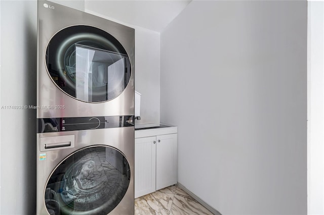 washroom featuring stacked washing maching and dryer, cabinet space, and marble finish floor