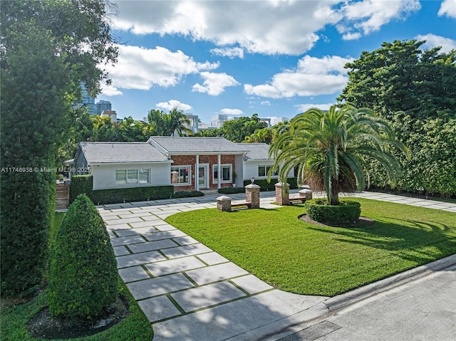 view of front of home featuring brick siding, driveway, and a front lawn