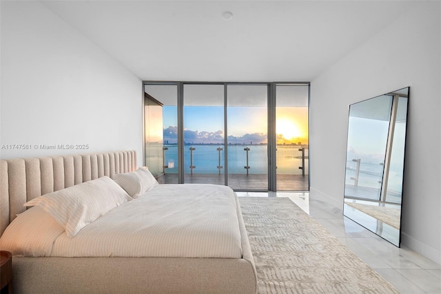 bedroom featuring access to exterior, floor to ceiling windows, a water view, light tile patterned flooring, and baseboards