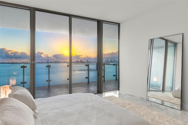 bedroom featuring access to exterior, floor to ceiling windows, a water view, and multiple windows