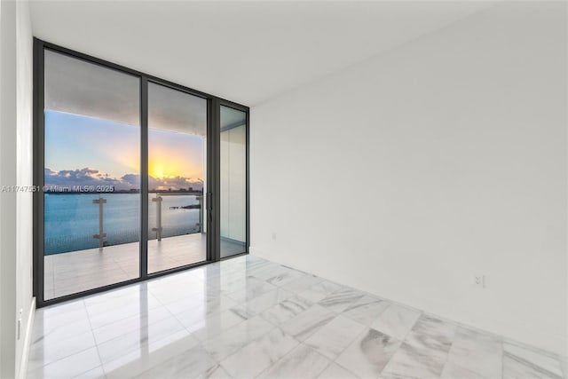 spare room featuring a water view and floor to ceiling windows