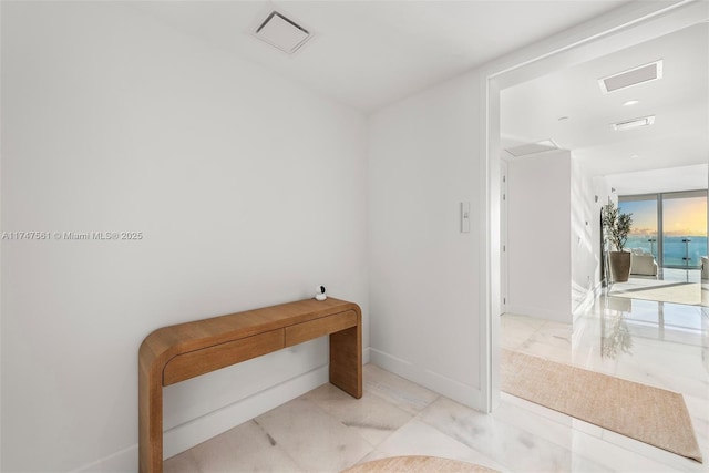 hall with marble finish floor, visible vents, and baseboards