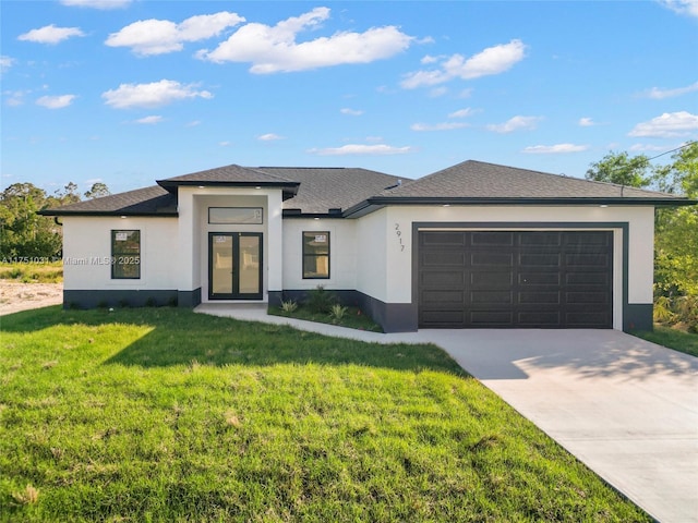 prairie-style house featuring a garage, driveway, a front yard, and stucco siding