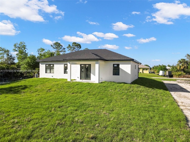 rear view of property featuring a yard and stucco siding