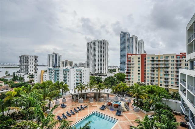 view of swimming pool with a view of city, a patio, and a community hot tub