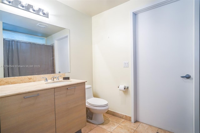 bathroom with tile patterned flooring, baseboards, vanity, and toilet