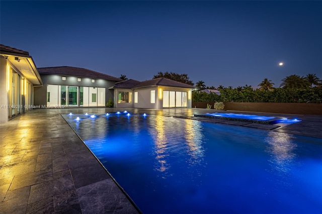 pool at twilight with a fenced in pool, fence, and a patio area