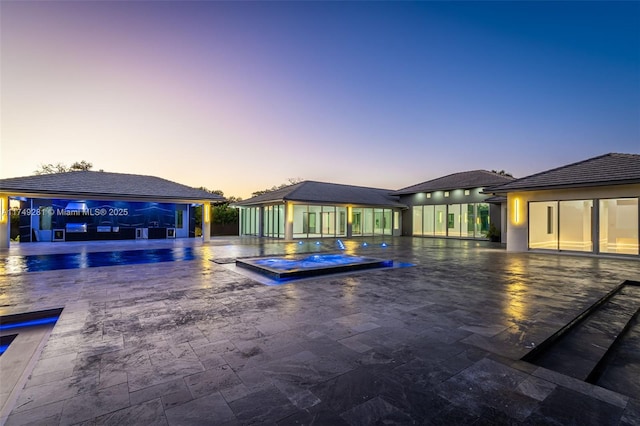 pool at dusk with an outdoor pool and an in ground hot tub