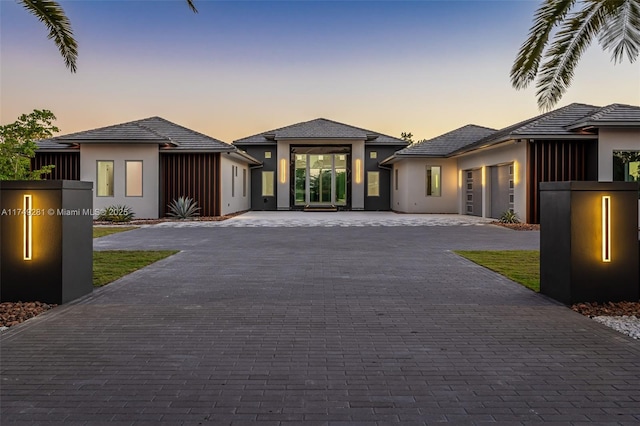 prairie-style house with decorative driveway, an attached garage, and stucco siding