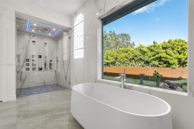 bathroom with a marble finish shower and a freestanding bath