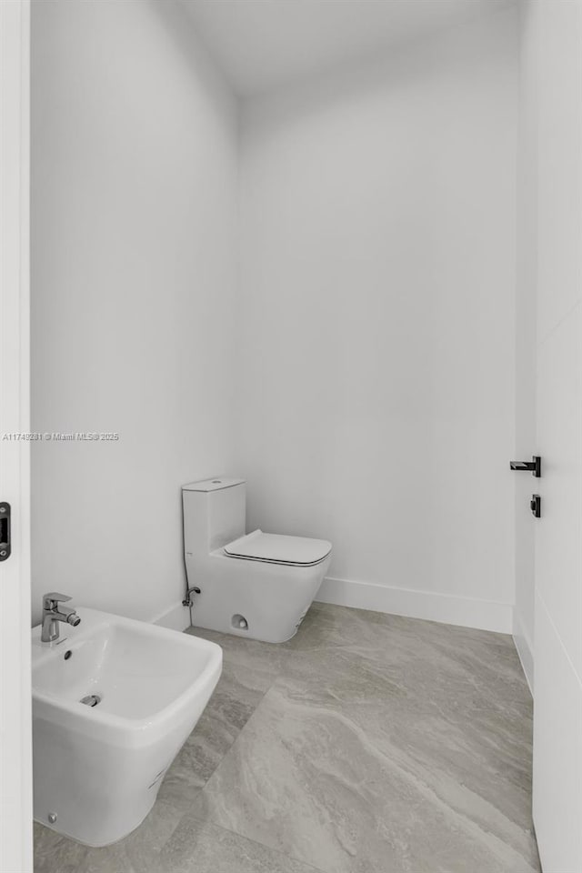 half bath featuring baseboards, a bidet, and toilet