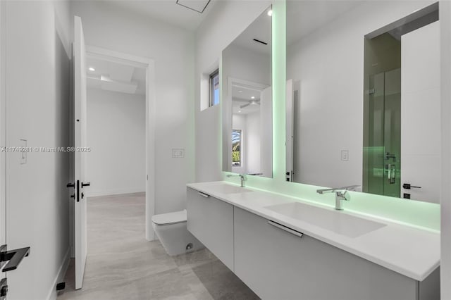 full bath featuring double vanity, a shower stall, toilet, and a sink