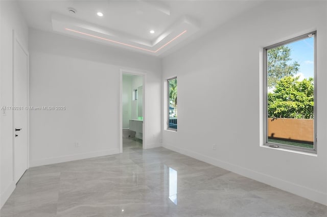 spare room featuring recessed lighting, baseboards, and a tray ceiling