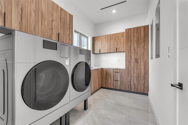 clothes washing area featuring baseboards, cabinet space, and washing machine and clothes dryer