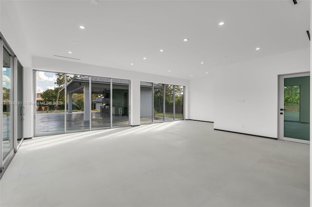 unfurnished living room featuring recessed lighting, plenty of natural light, and concrete flooring