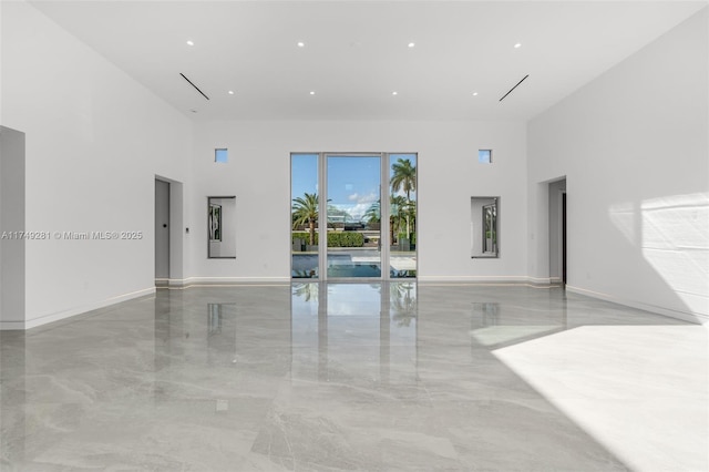 spare room with baseboards, marble finish floor, and a towering ceiling