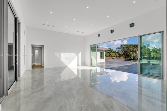 empty room featuring marble finish floor and a high ceiling