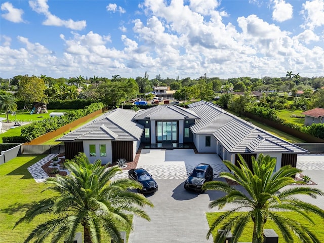 view of front of property featuring a tile roof, fence, driveway, and stucco siding