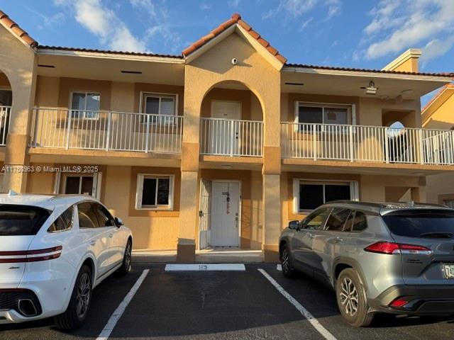 view of front of house with uncovered parking, a tile roof, and stucco siding