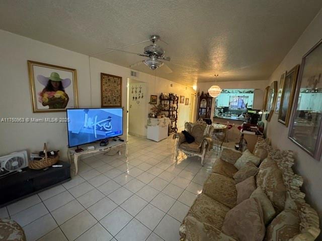 living room featuring light tile patterned floors, ceiling fan, and a textured ceiling