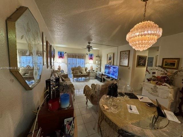 interior space with a textured ceiling, ceiling fan with notable chandelier, and light tile patterned flooring