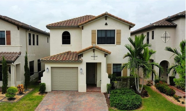 mediterranean / spanish house featuring a tiled roof, decorative driveway, and stucco siding