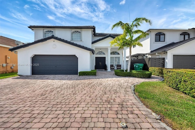 view of front of home featuring a garage, a tiled roof, a porch, and stucco siding