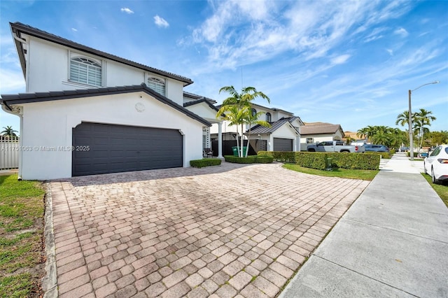 view of front of home with a garage, decorative driveway, and stucco siding