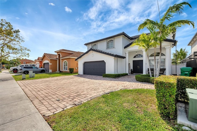 view of front of property featuring decorative driveway, stucco siding, a front yard, fence, and a garage