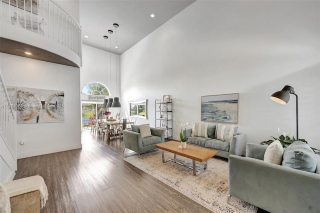 living area with recessed lighting, baseboards, a high ceiling, and wood finished floors