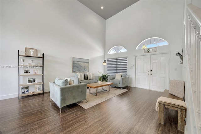 living area with wood finished floors, a towering ceiling, and baseboards