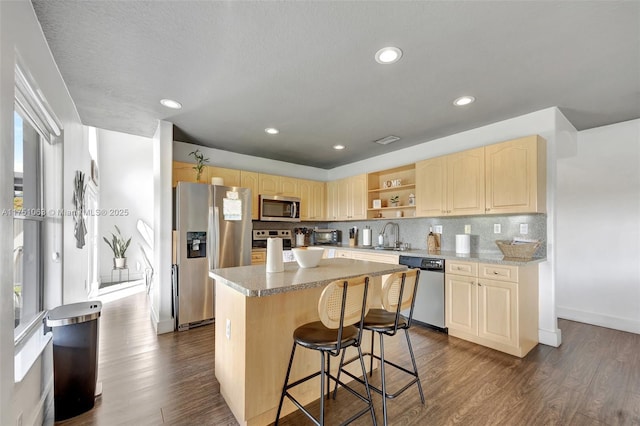 kitchen with appliances with stainless steel finishes, light brown cabinets, dark wood finished floors, and tasteful backsplash