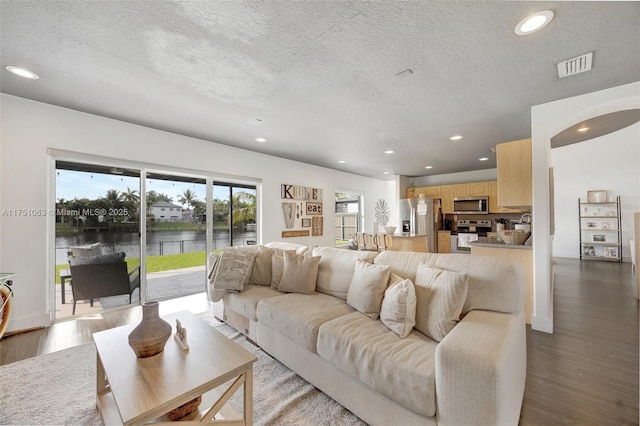 living area with recessed lighting, visible vents, a textured ceiling, and wood finished floors