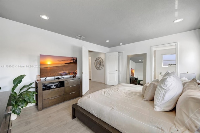 bedroom with light wood-style floors, recessed lighting, visible vents, and a textured ceiling