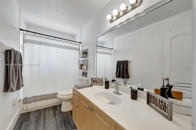 full bathroom featuring curtained shower, toilet, a textured ceiling, vanity, and wood finished floors