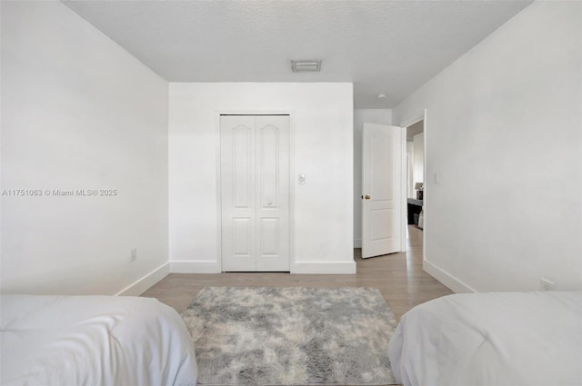 bedroom featuring a textured ceiling, baseboards, and wood finished floors