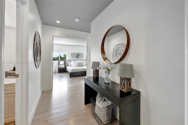 hall with light wood finished floors, baseboards, and recessed lighting