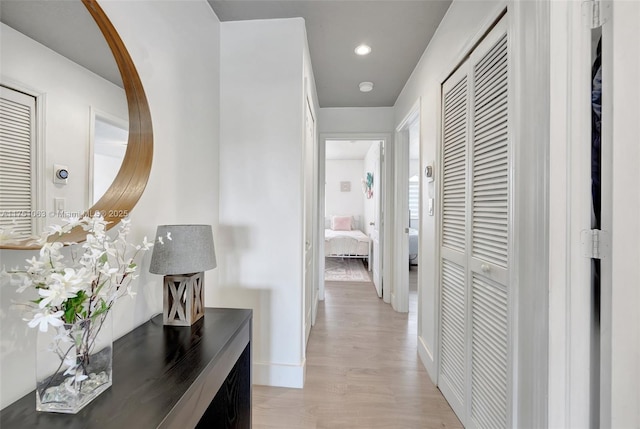 hallway featuring light wood finished floors, baseboards, and recessed lighting