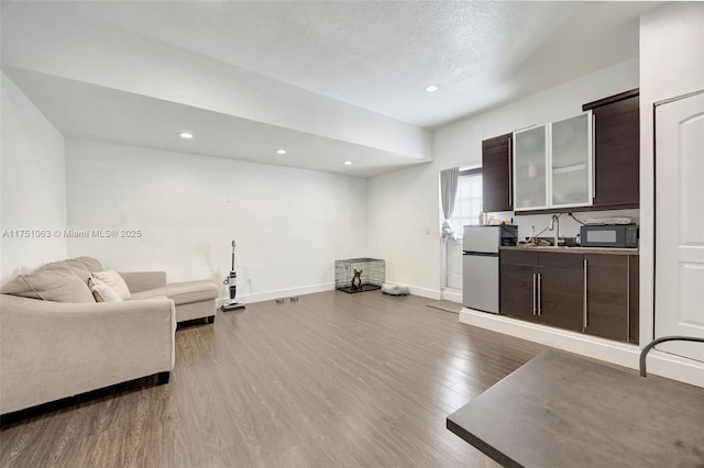 living room with recessed lighting, a textured ceiling, baseboards, and wood finished floors