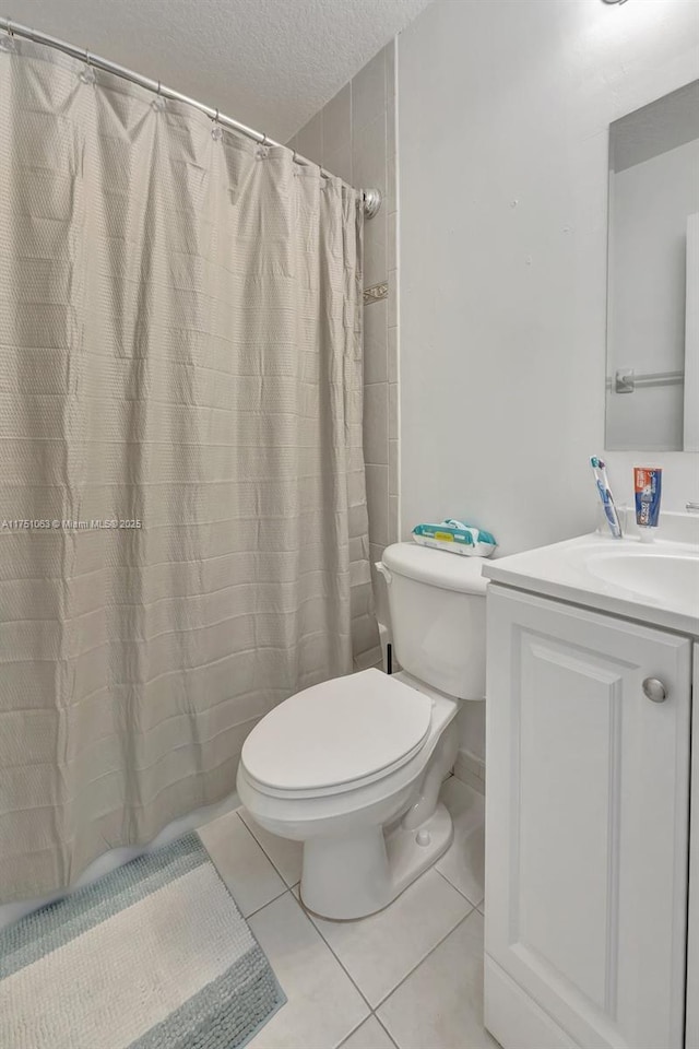 bathroom with a textured ceiling, vanity, toilet, and tile patterned floors