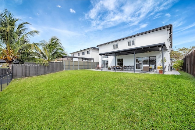 back of property featuring a yard, a fenced backyard, a ceiling fan, and stucco siding