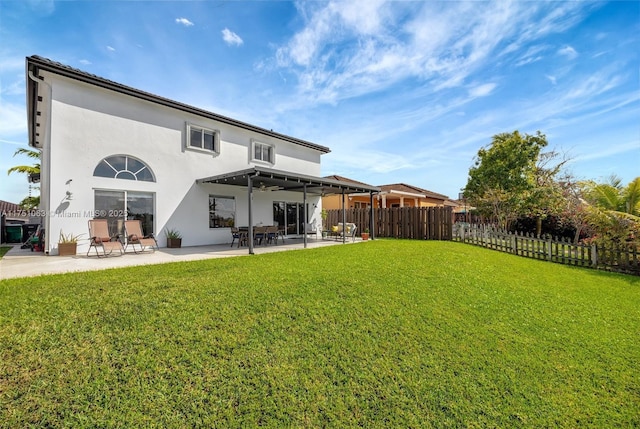 rear view of house with a patio, a yard, fence, and stucco siding