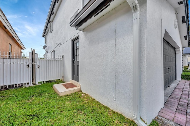 view of side of property with a yard, a gate, fence, and stucco siding