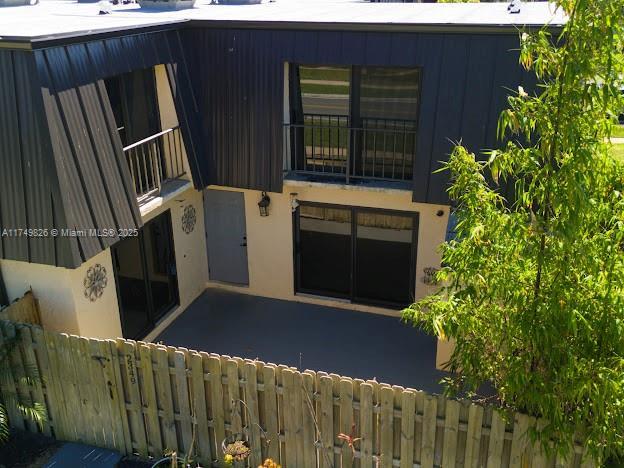 view of front facade with a patio, fence, a balcony, and stucco siding