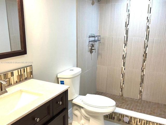 full bathroom with tiled shower, vanity, and toilet