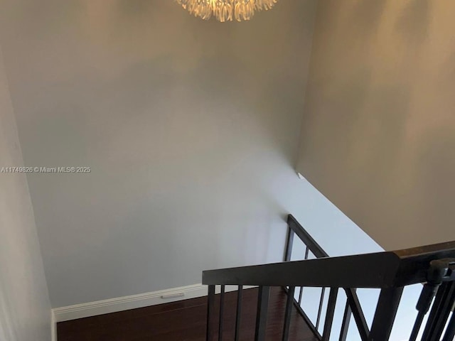 stairs featuring an inviting chandelier, wood finished floors, and baseboards