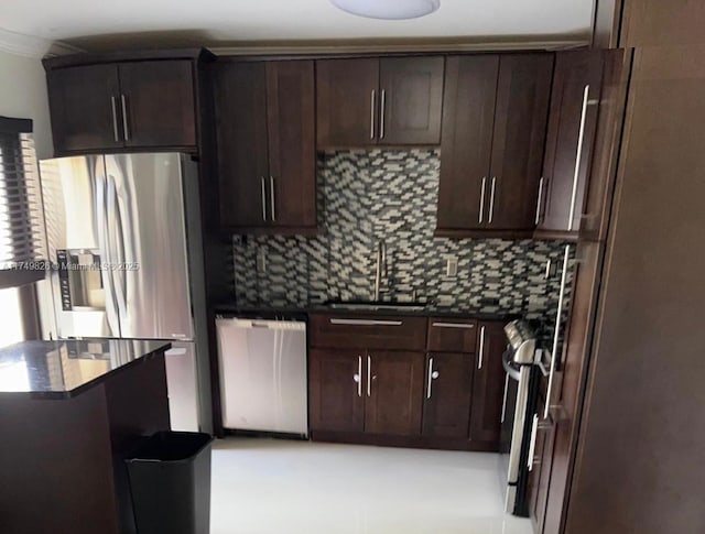 kitchen with dark countertops, dark brown cabinetry, stainless steel appliances, and a sink