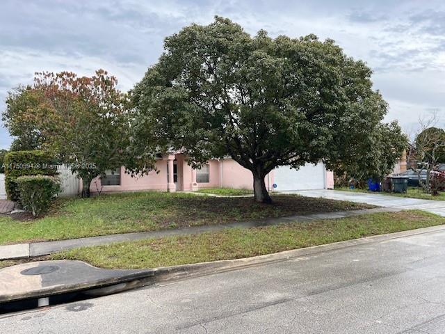 obstructed view of property with concrete driveway, a front lawn, and stucco siding