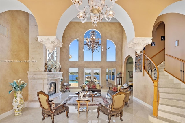 living room featuring a chandelier, arched walkways, a towering ceiling, a high end fireplace, and stairs