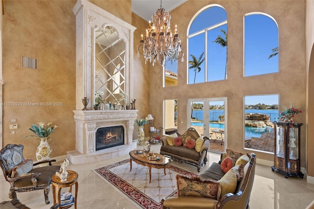 living area featuring a water view, a high end fireplace, visible vents, baseboards, and ornamental molding